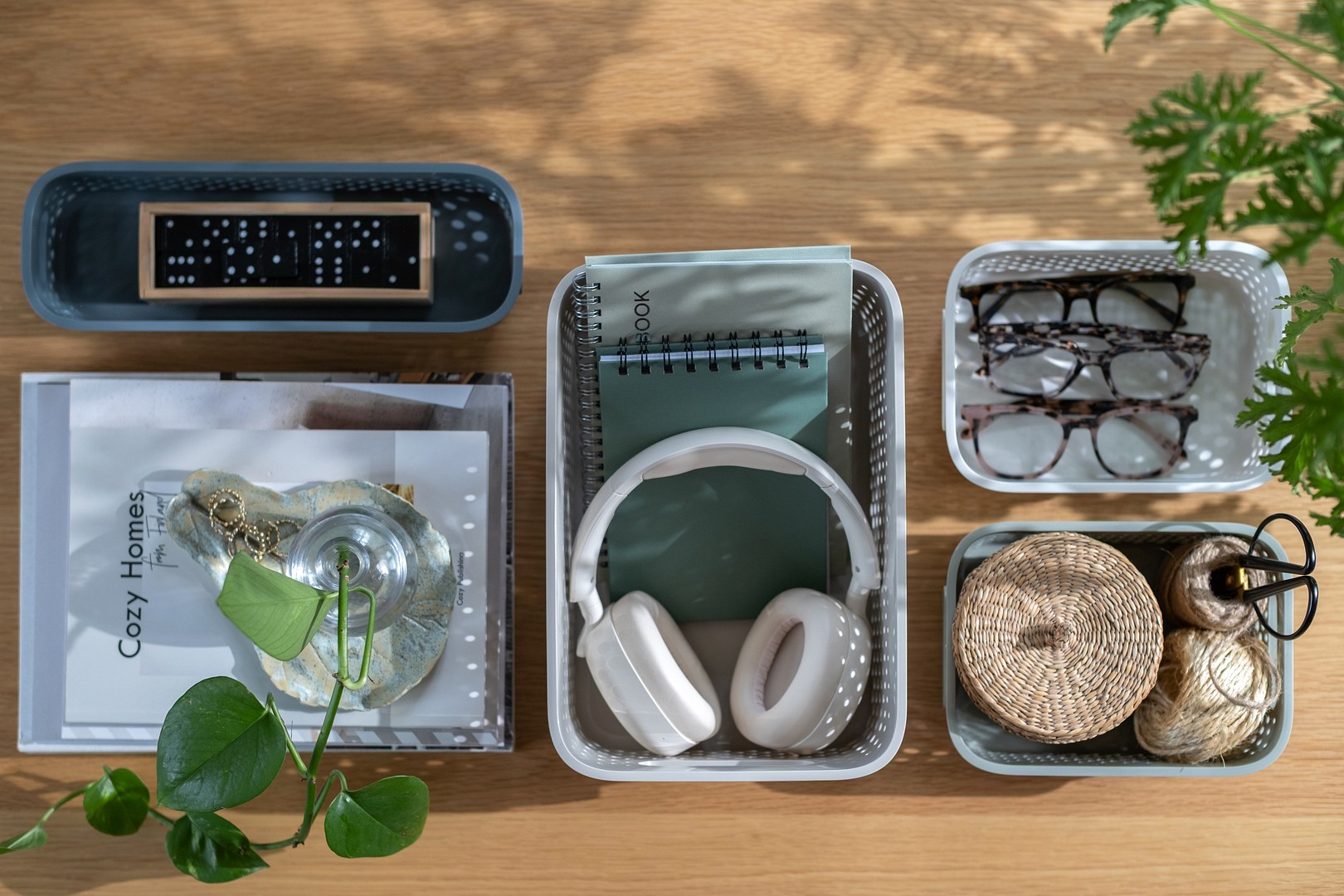 SmartStore Essence storage baskets in multiple sizes. Inside them are headphones, notebooks, eyeglasses and other small household items.